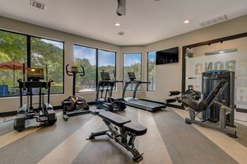a gym with cardio equipment and windows with a view